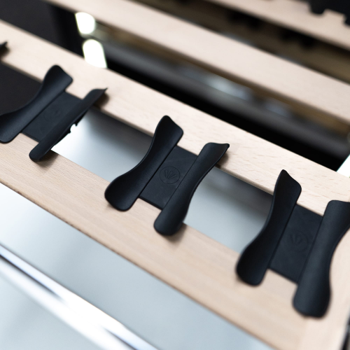 Close-up of wooden slatted wine cellar rack with black plastic spacers in kitchen appliances collection