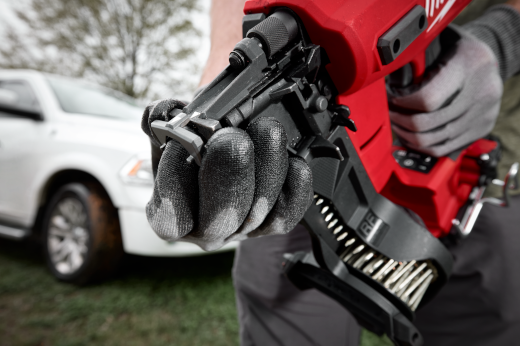 Gloved hand adjusting vinyl siding tip on red Milwaukee M18 nailer for siding and fastening tools in home improvement