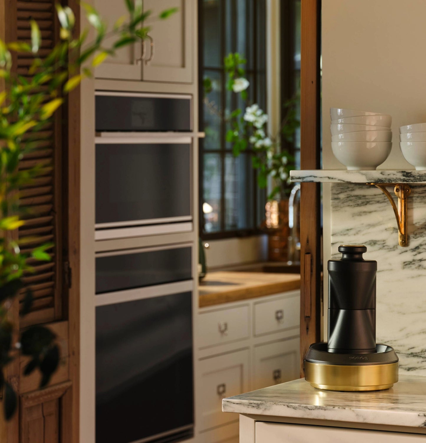 Minimalist built-in wall oven with black glass panels integrated into light cabinetry in a warm kitchen setting
