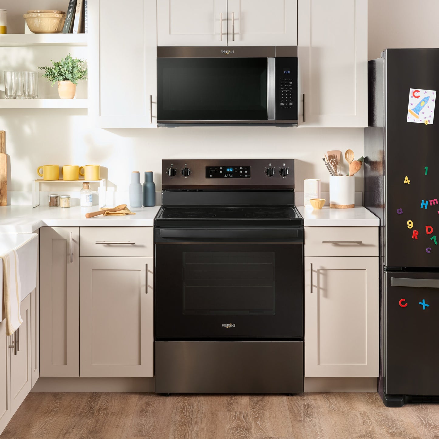 Whirlpool black stainless steel over the range microwave installed above matching electric range in bright kitchen setting