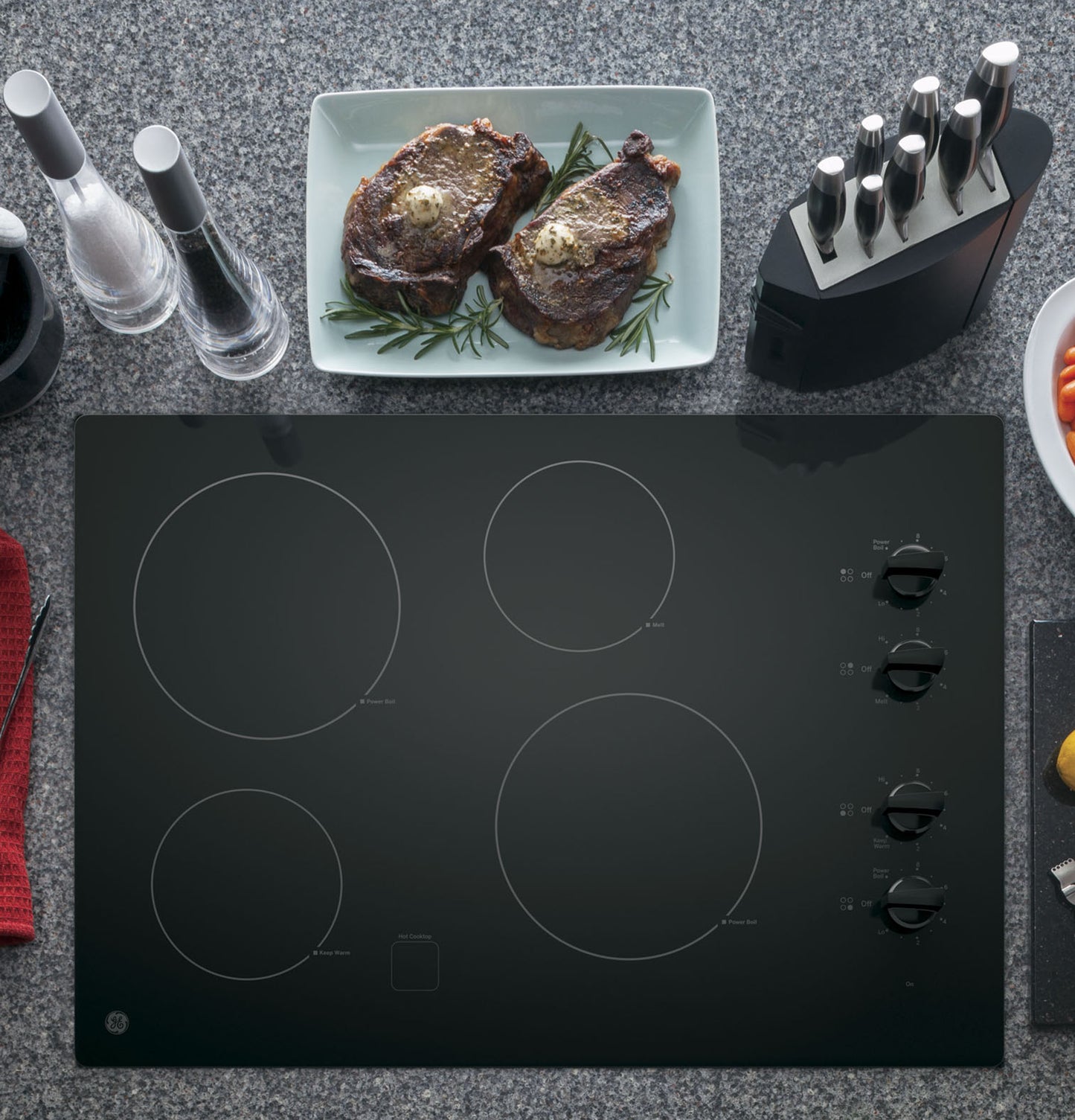 Black built-in electric cooktop with four radiant heating zones and knob controls in Kitchen & Cooktops collections