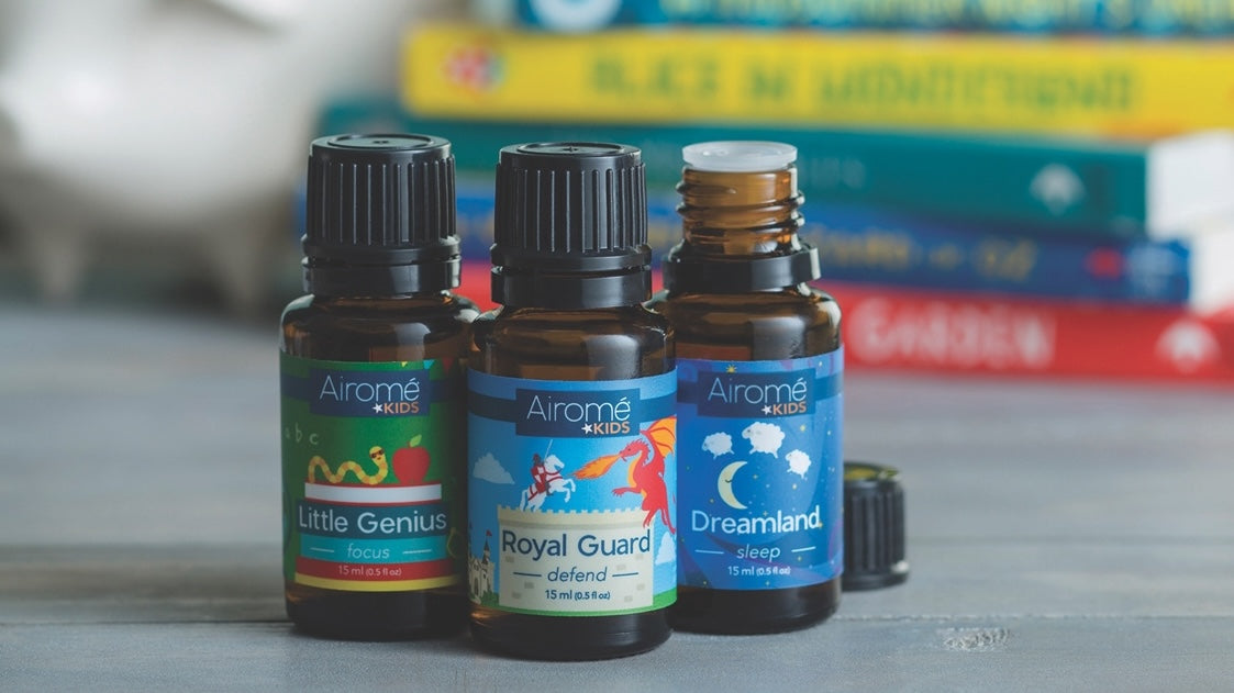 Three small essential oil bottles with colorful labels on a grey surface against blurred books in home decor and under $50 collections
