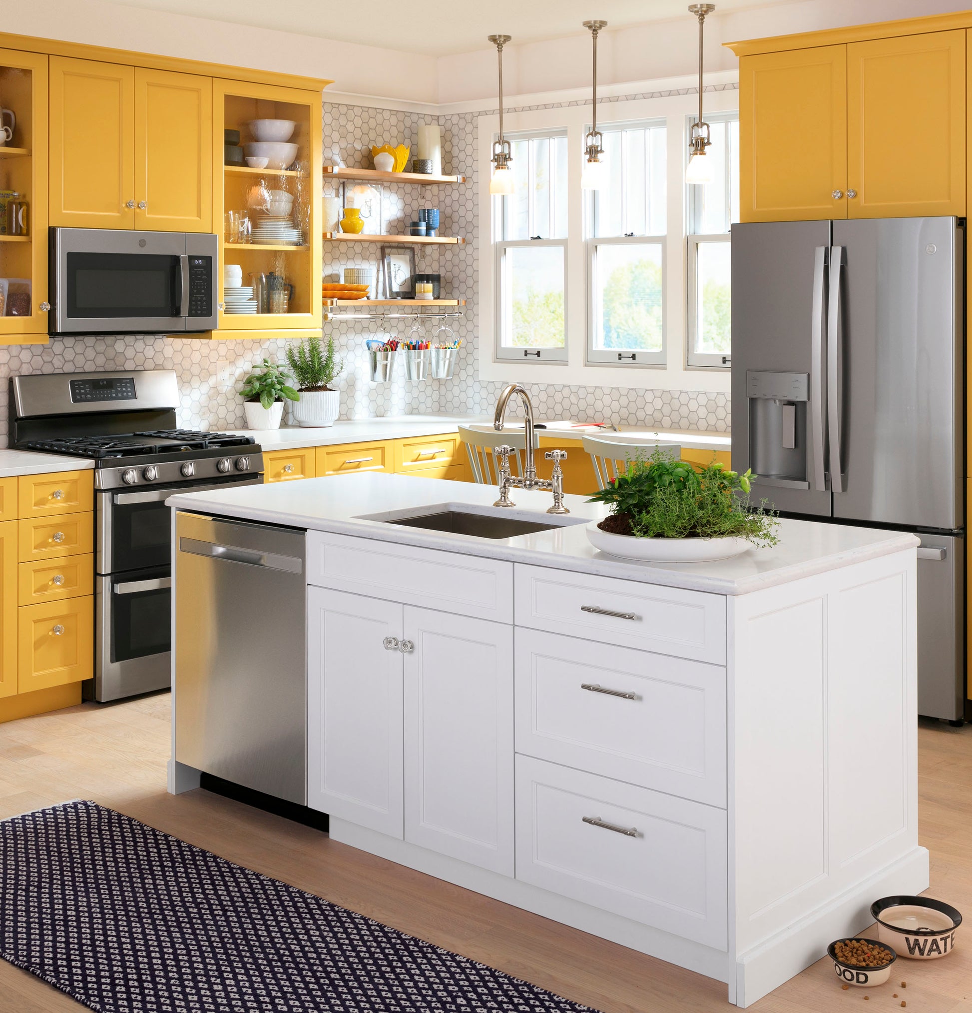Modern kitchen with yellow cabinetry featuring a fingerprint resistant over-the-range microwave and stainless steel appliances collection