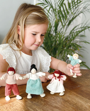 Child playing with four fabric and wooden dolls from the pretend play toys collection under $50 in toys and games