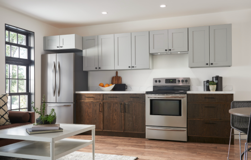 modern kitchen with stainless steel appliances dark wood lower cabinets and light gray upper cabinets in home improvement setting