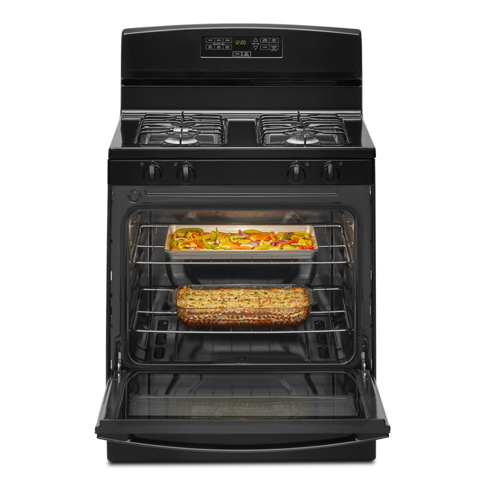 Black freestanding 30-inch gas range with two burners and open oven showing baked casserole and roasted vegetables inside