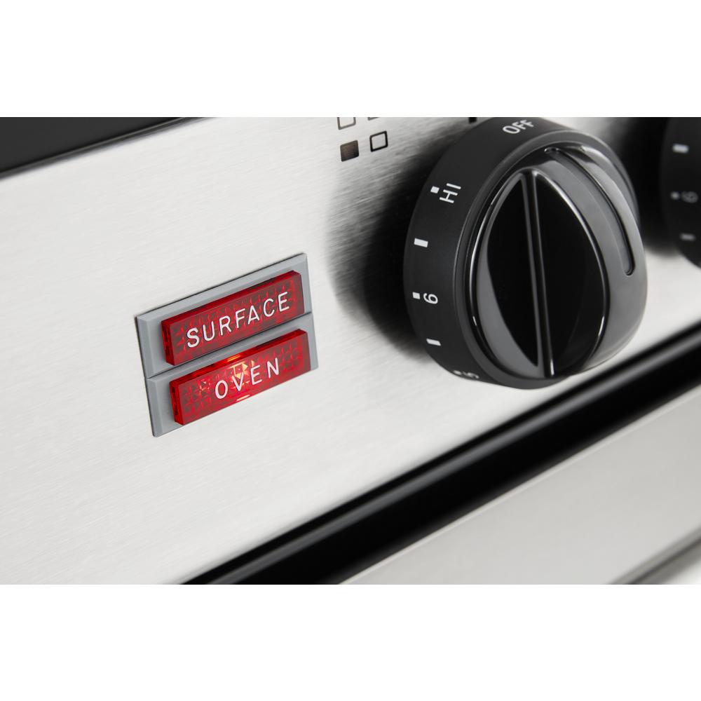 Close-up of stainless steel electric range control panel showing red surface and oven indicator lights with black knob for kitchen appliances