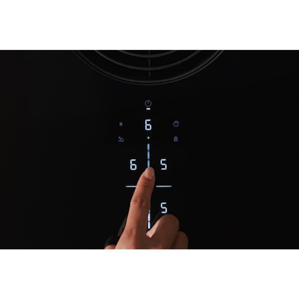 Finger adjusting digital touch control panel on black induction downdraft cooktop in modern kitchen setting