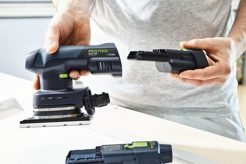 Person attaching a rechargeable battery to a cordless orbital sander for tools and home improvement use