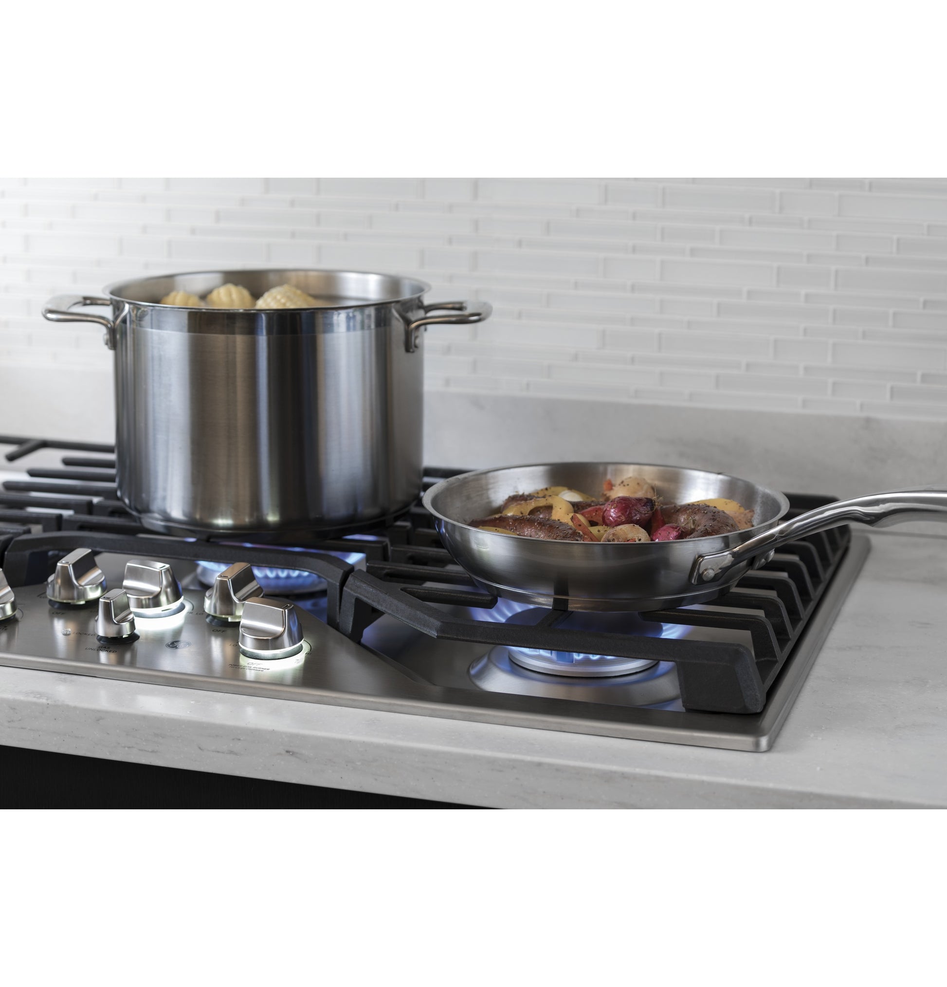 Stainless steel pot and skillet cooking on 36-inch built-in gas cooktop with five burners in modern kitchen setting