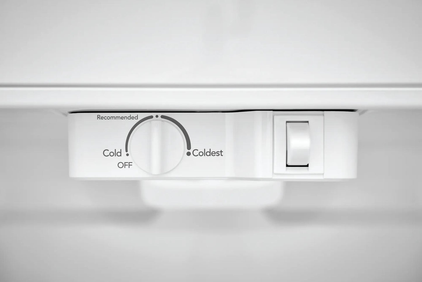 Close-up of white temperature control dial and light switch inside a top freezer refrigerator in Appliances collection