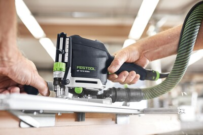 Person operating Festool OF 1010 REBQ-Set router with dust extraction for precise woodworking in a workshop setting