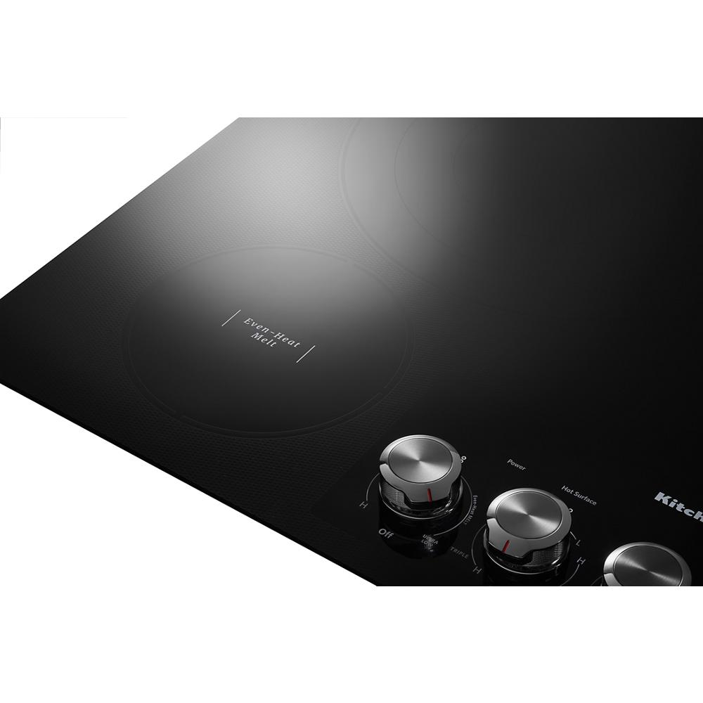 Black electric cooktop with five radiant elements and stainless steel knob controls in kitchen appliances collection