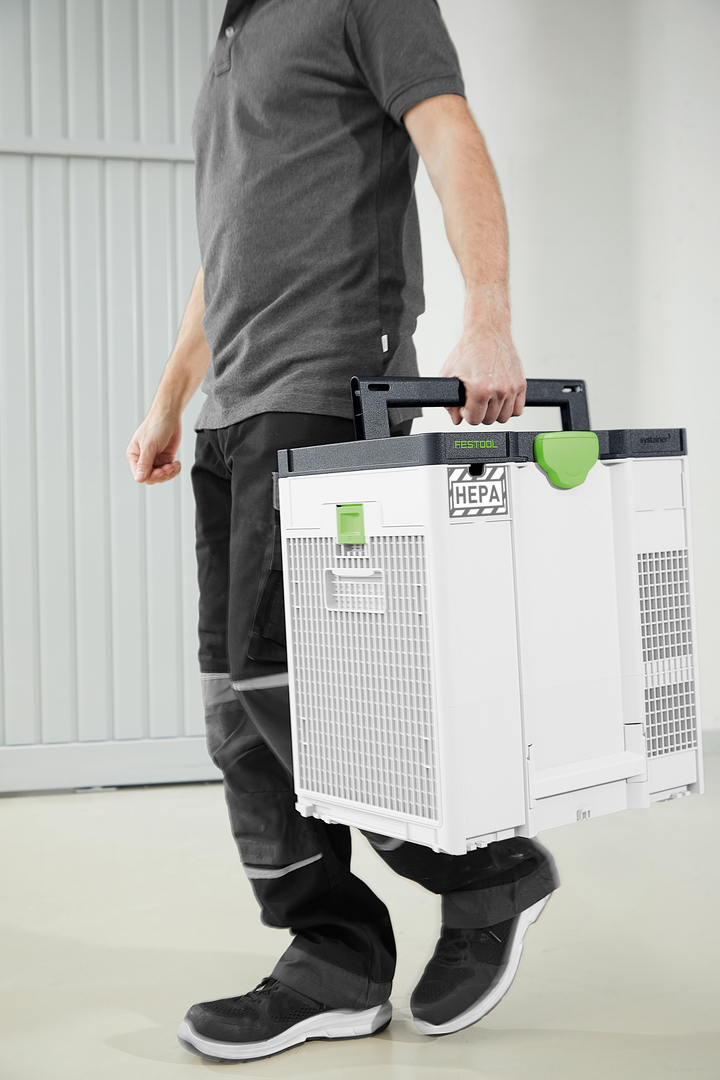 Person carrying a compact white and green HEPA air filter for dust management in woodworking tool collections