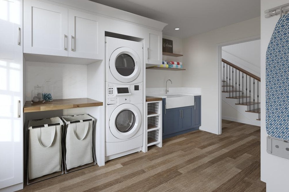 White stack washer and dryer set in spacious laundry room with blue cabinetry, wooden countertop, and sorting baskets
