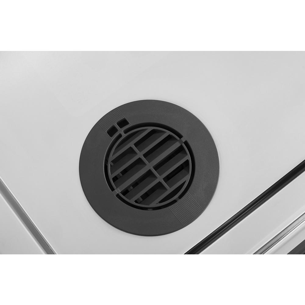 Close-up of black circular dishwasher filtration vent integrated in stainless steel interior for kitchen appliances