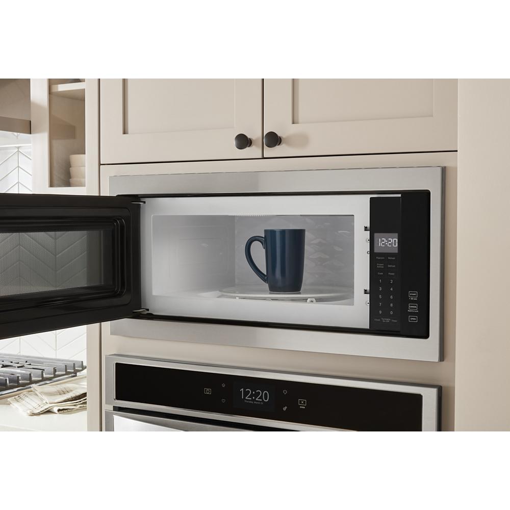 Built-in stainless steel microwave with slim trim kit and digital display showing blue mug inside in kitchen setting