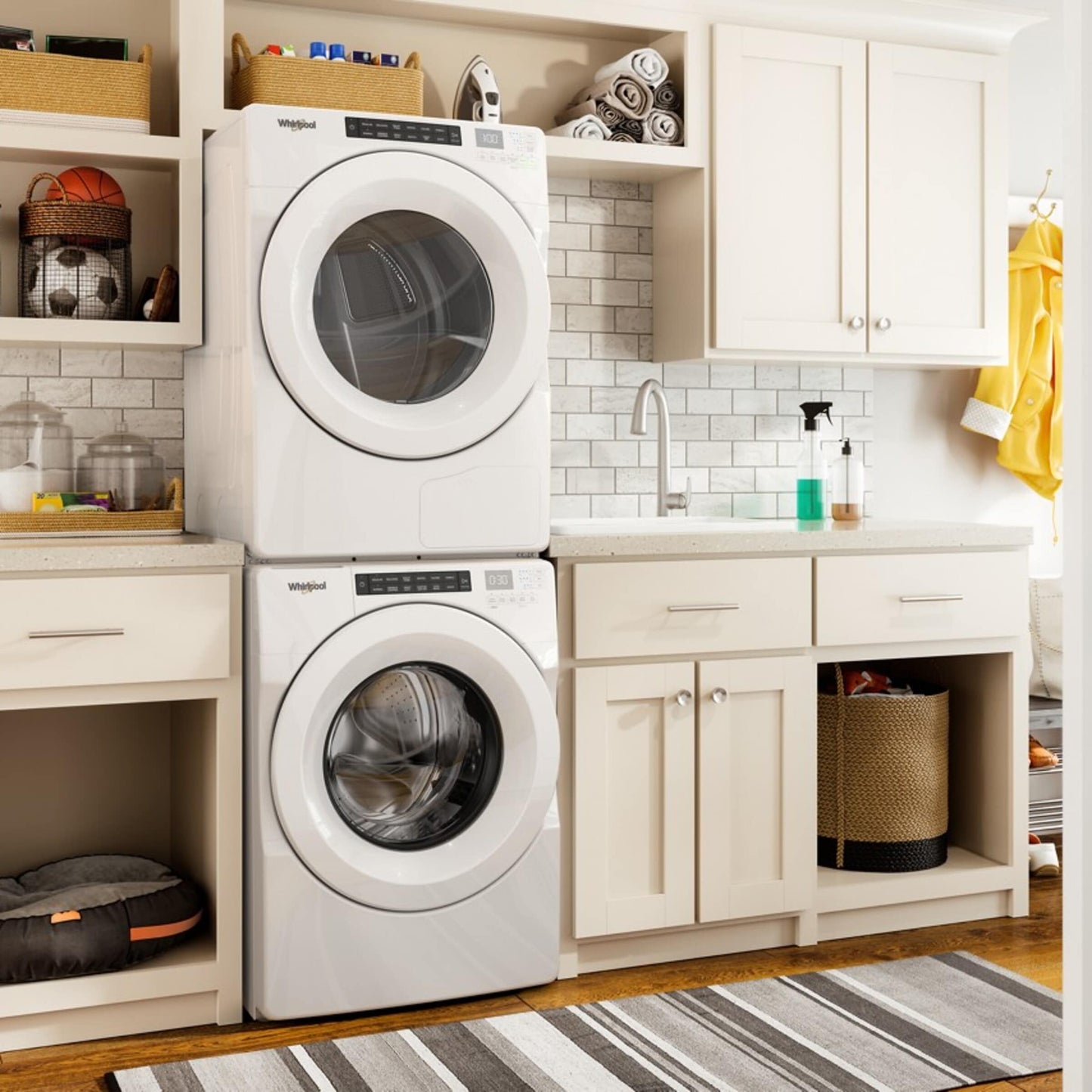 Stacked white front load washer and heat pump dryer in bright laundry room with cabinetry and countertop space