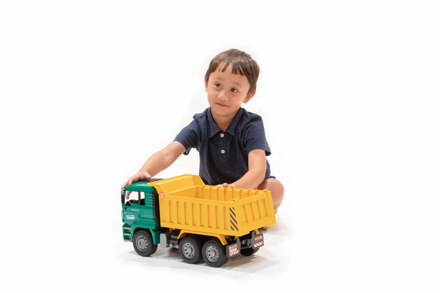 Young child playing with green and yellow MAN TGA tip-up truck toy in Toys & Games and Vehicles collection