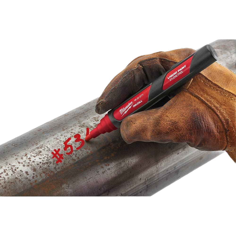 Gloved hand using red liquid paint marker to write on rough metal pipe in woodworking and hand tools collections