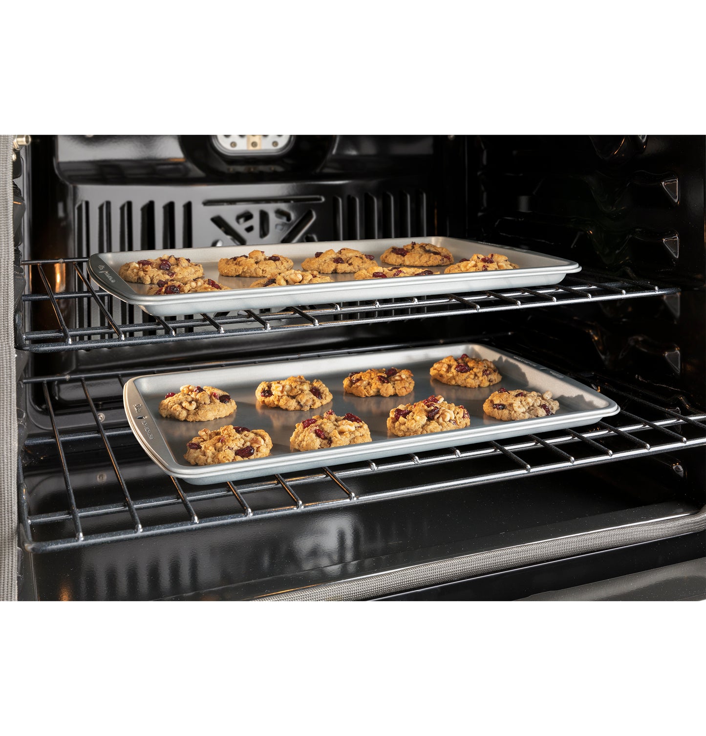 View inside double wall oven with two baking sheets holding cookies on racks in kitchen appliances collection