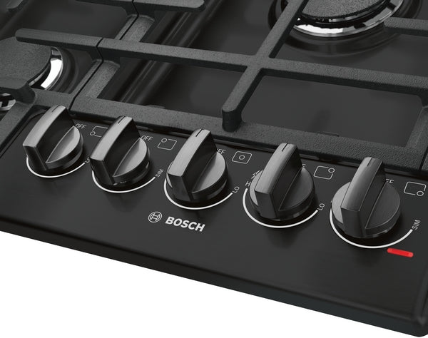 Black gas cooktop control panel with five push-to-turn knobs and porcelain enamel cast iron grates in Bosch appliances collection