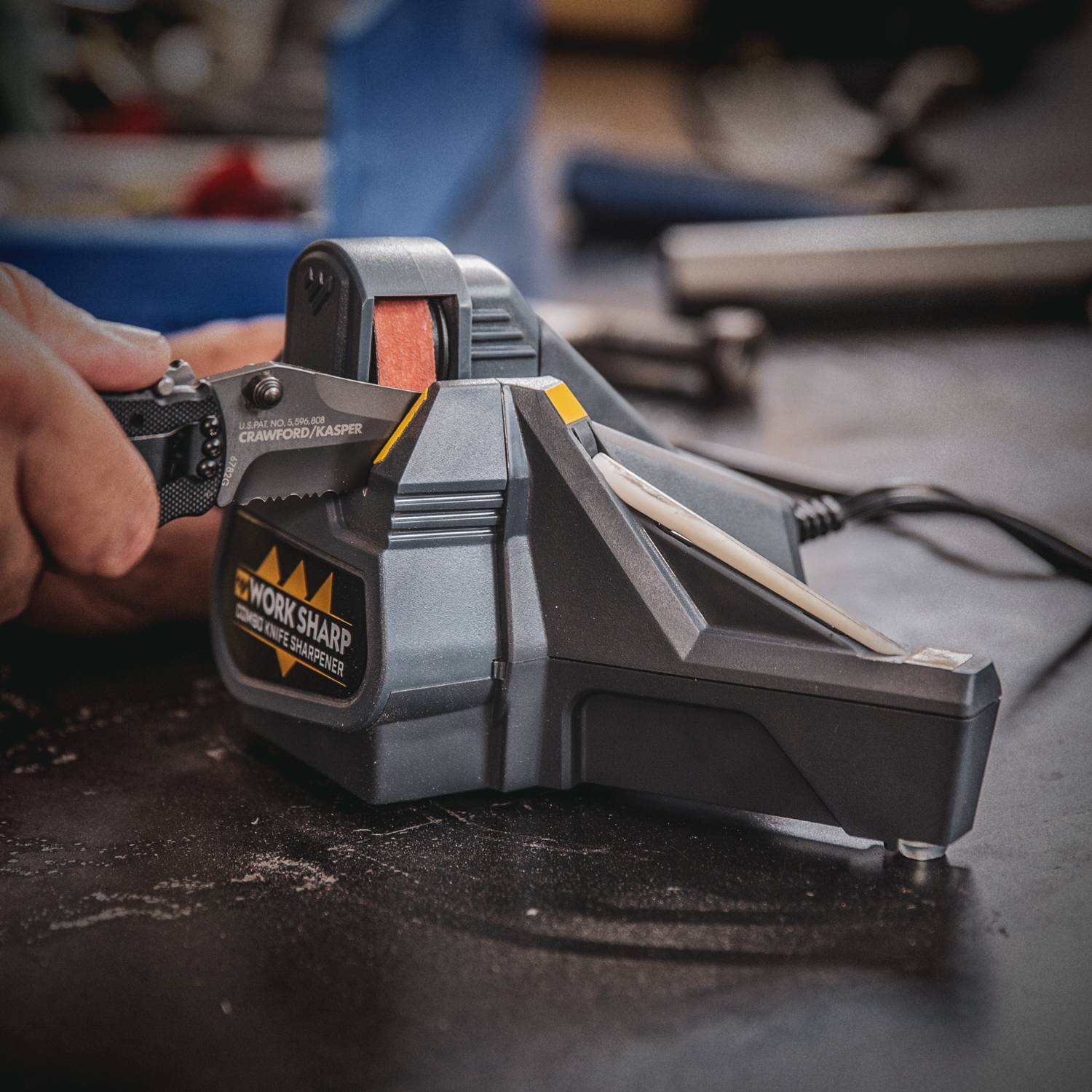 Person sharpening a serrated knife on a black and yellow electric combo sharpener from woodworking tools collection