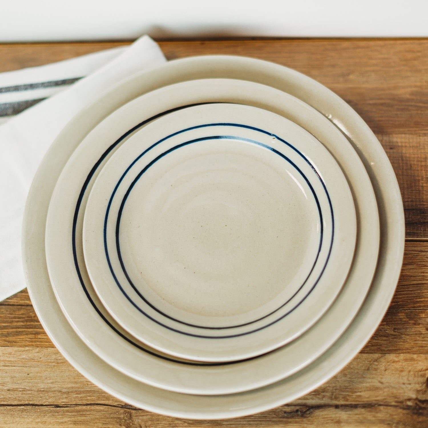 Set of three cream stoneware plates with blue stripes, part of kitchenware and under $50 collections