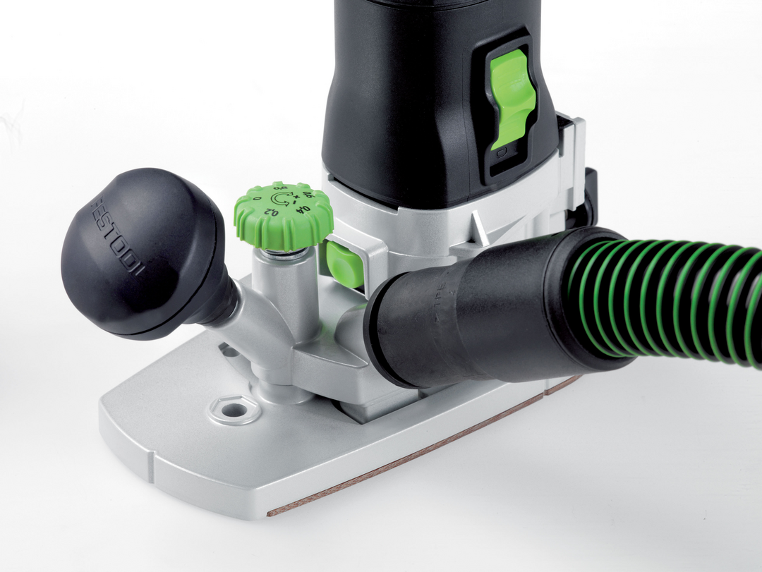 Close-up of a green-accented trim router base with dust extraction hose for precise home improvement woodworking tasks
