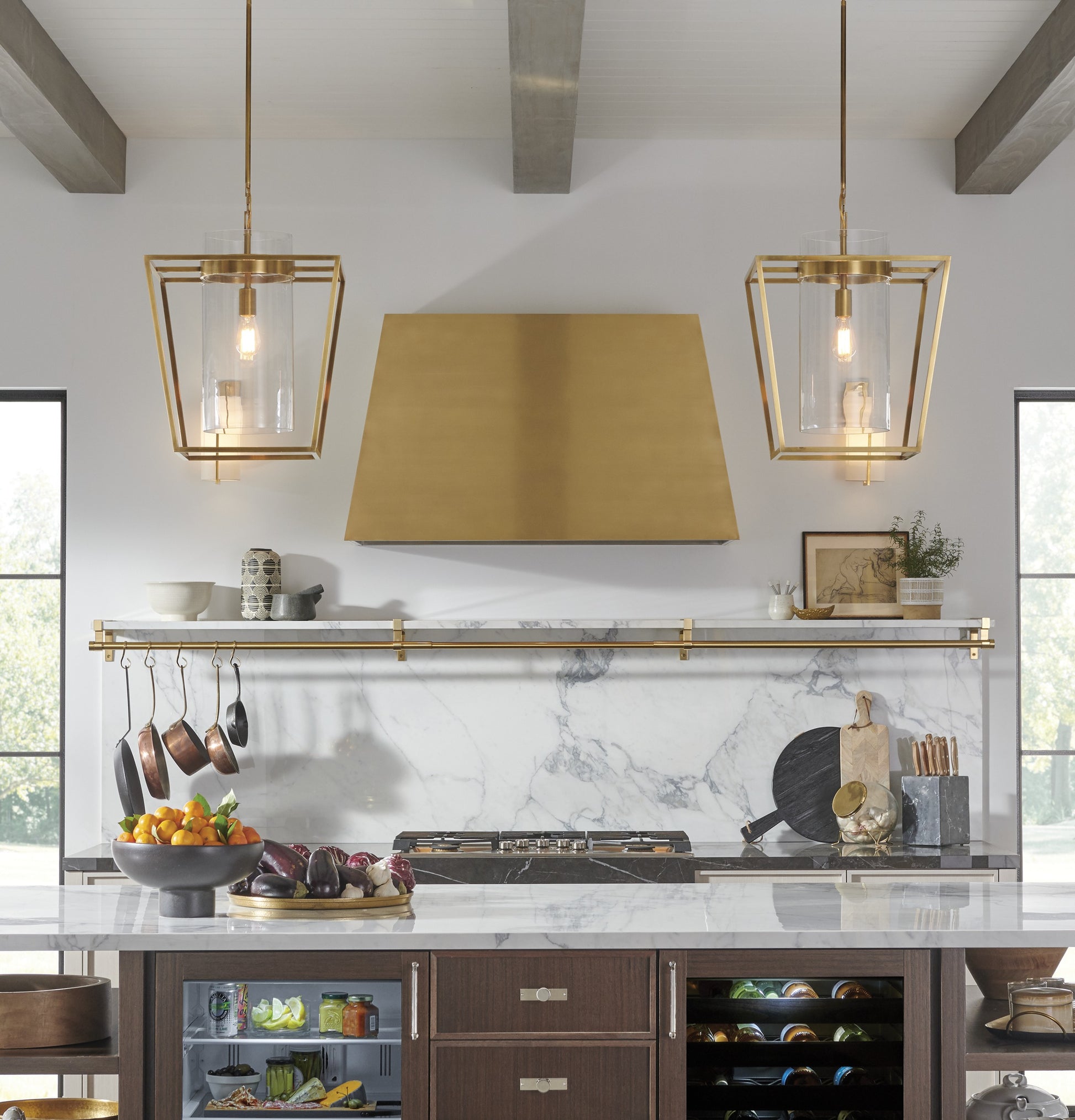 Brass kitchen hood above marble backsplash with modern pendant lights in kitchen and home improvement collections