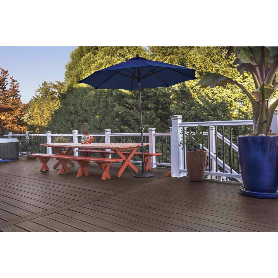 Outdoor deck with dark roast TimberTech square shoulder boards, white railing, picnic table, and blue umbrella under trees