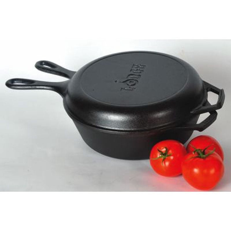 Black cast iron combo cooker with lid and two handles next to fresh red tomatoes for kitchen use