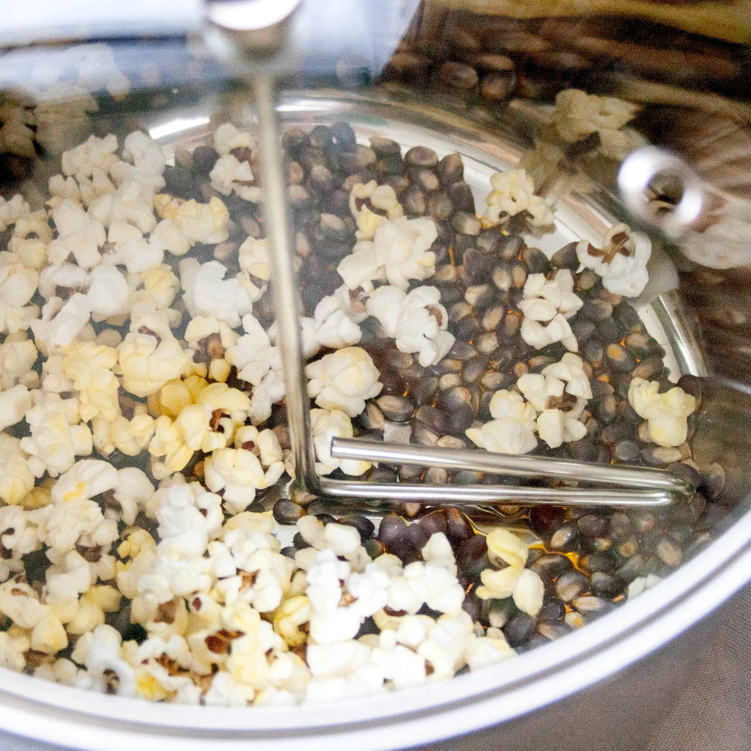 Partially popped and unpopped kernels inside stainless steel popcorn popper from small kitchen appliances collection