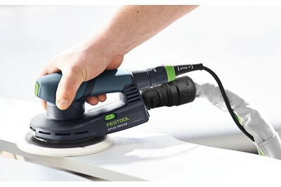 Handheld Festool electric sander connected to a dust extractor hose for woodworking dust management tasks