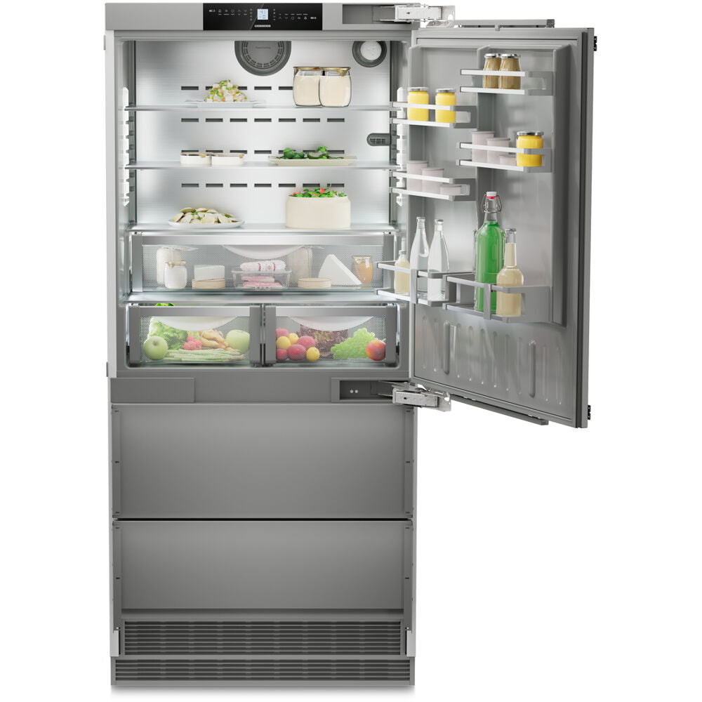 Open stainless steel built-in refrigerator with adjustable glass shelves, clear crispers, and bottom freezer drawers in Appliances collection
