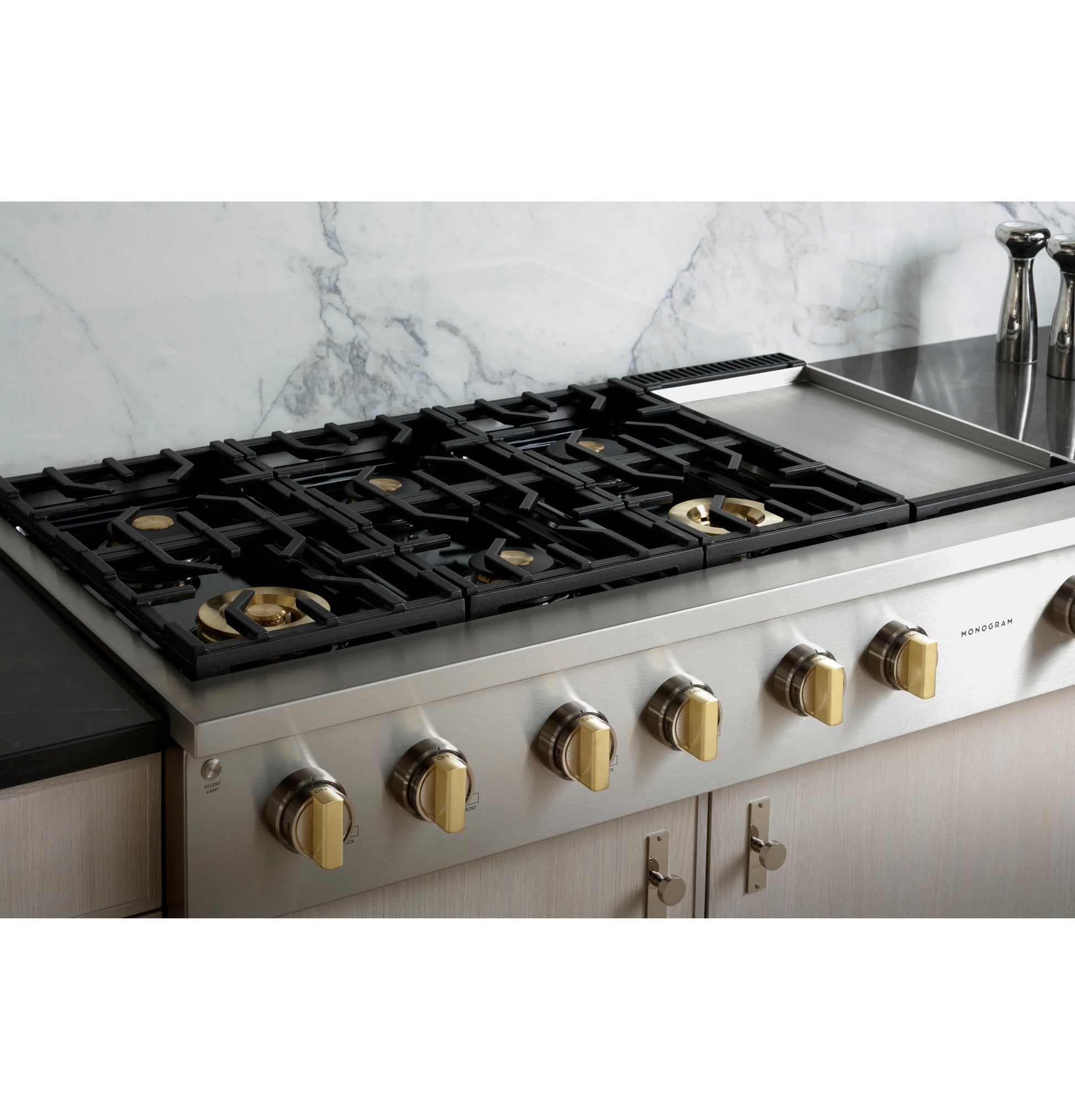 Stainless steel professional gas cooktop with six burners and griddle in modern kitchen setting collections