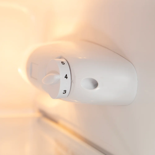 close-up of a white temperature control dial inside a refrigerator for precise cooling adjustment in appliances