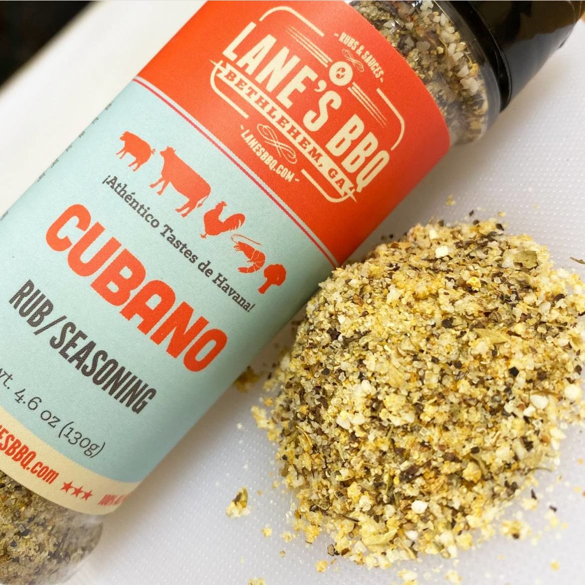 Bottle of Lane's Cubano BBQ rub seasoning with coarse textured spice blend spilled beside it