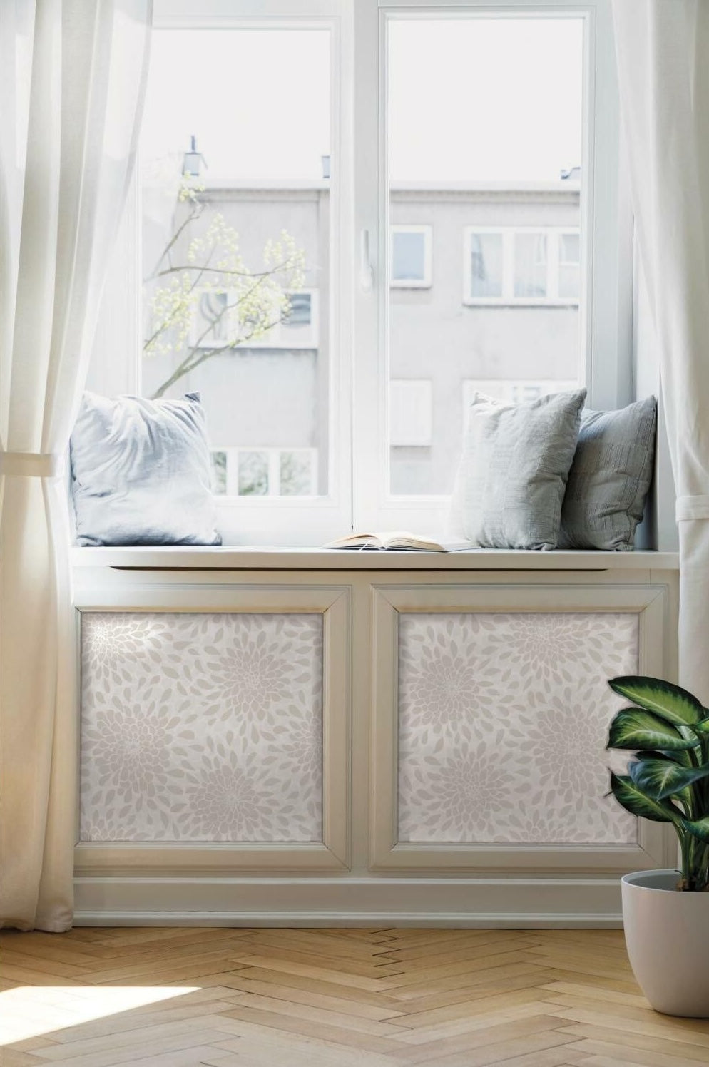 Sunlit window seat with pastel cushions, neutral floral peel and stick wallpaper panels, and a potted green plant nearby