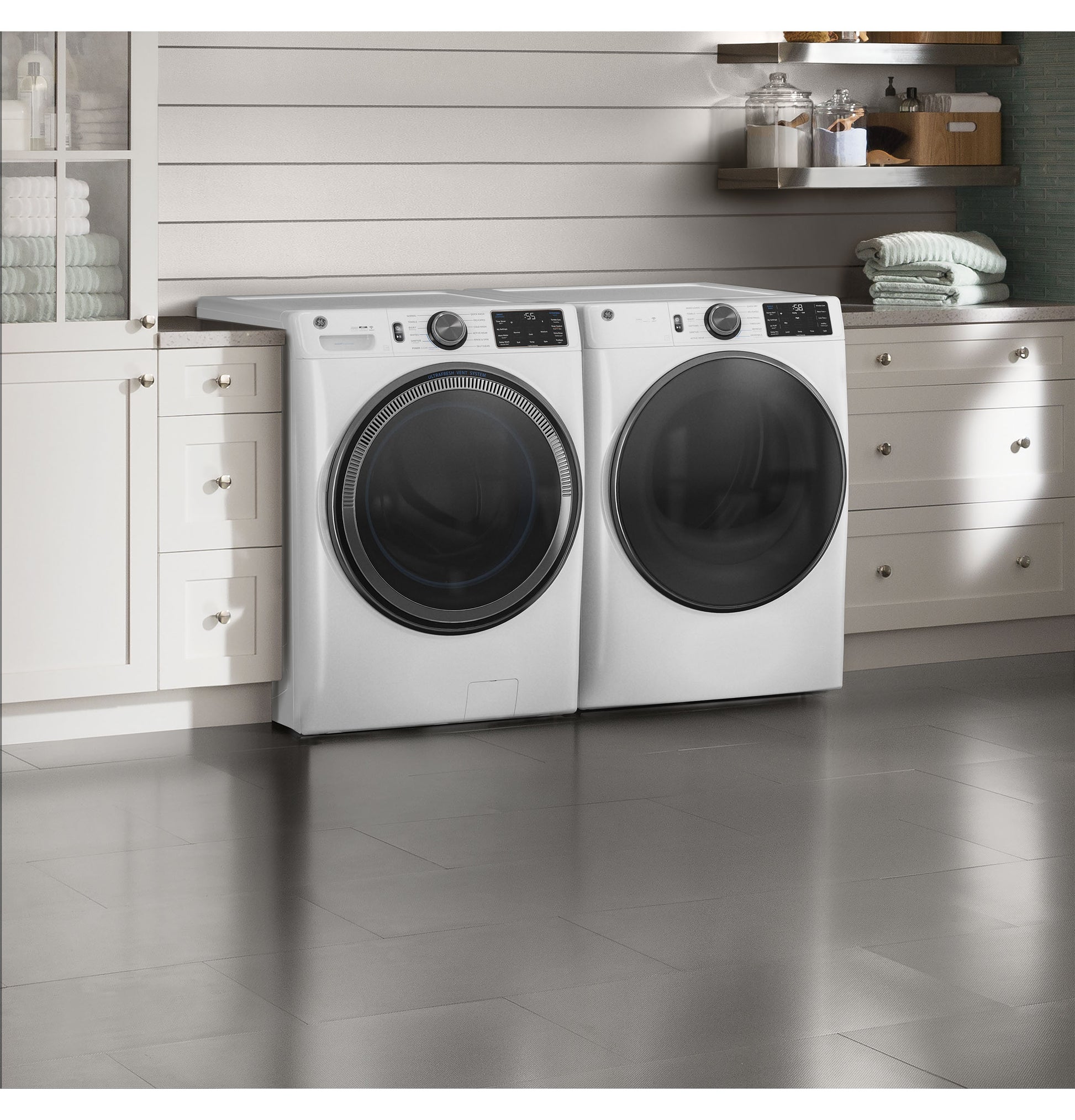 White front load washer and dryer set with digital controls in a bright modern laundry room setting