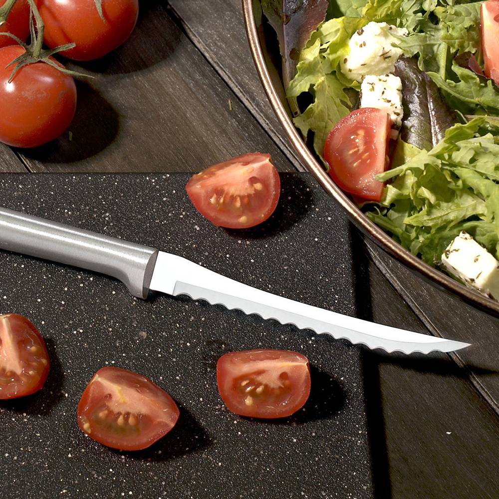 Serrated blade slicer with a solid aluminum handle resting on a cutting board with cherry tomatoes and a bowl of salad, ideal for kitchenware and utensils collections.