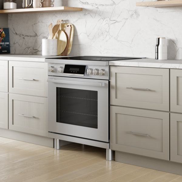 Stainless steel induction freestanding range with ergonomic tilted display and metal knobs in stylish kitchen setting