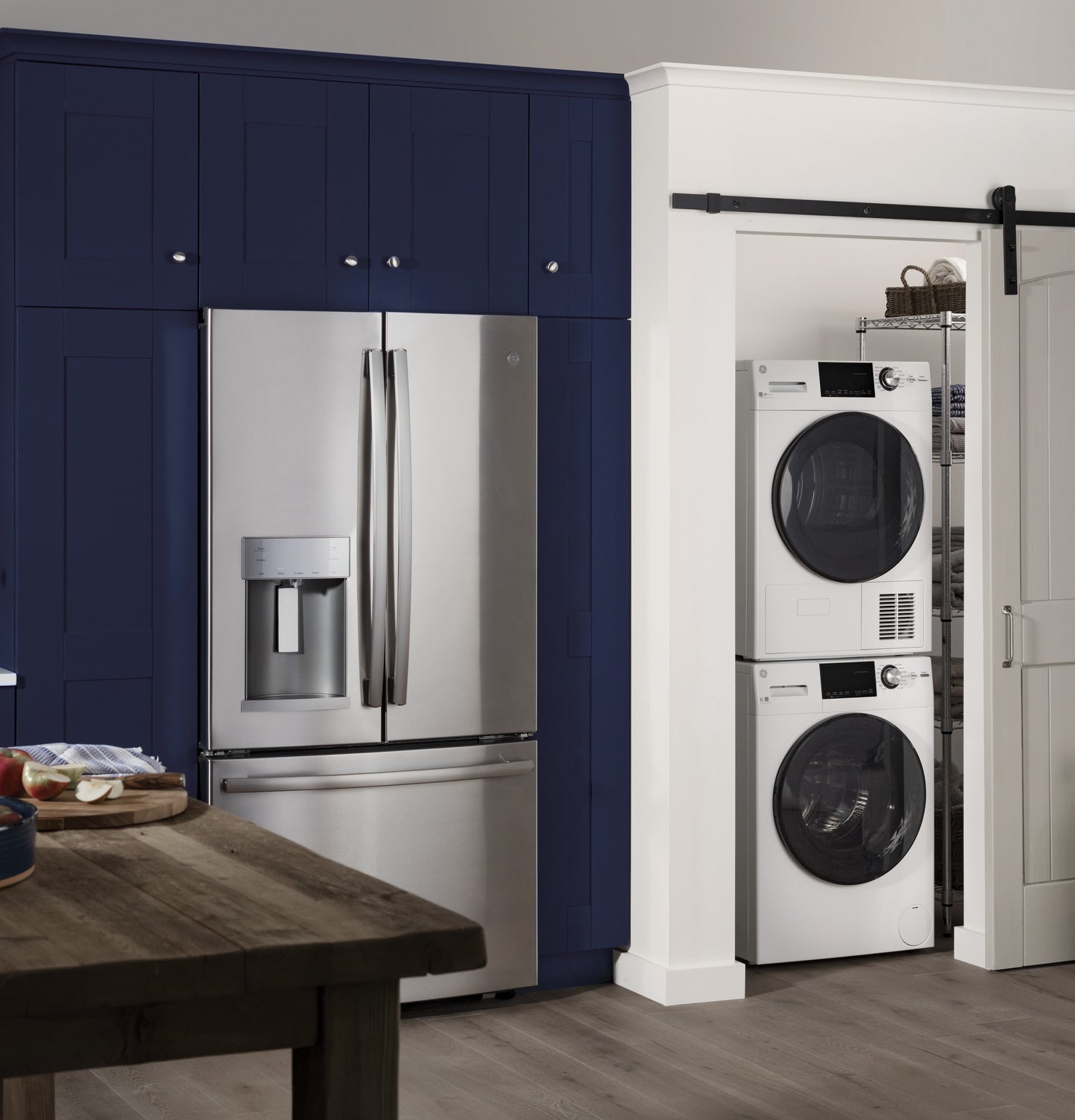 Stacked white front load washer and dryer in laundry closet next to stainless steel refrigerator in modern kitchen