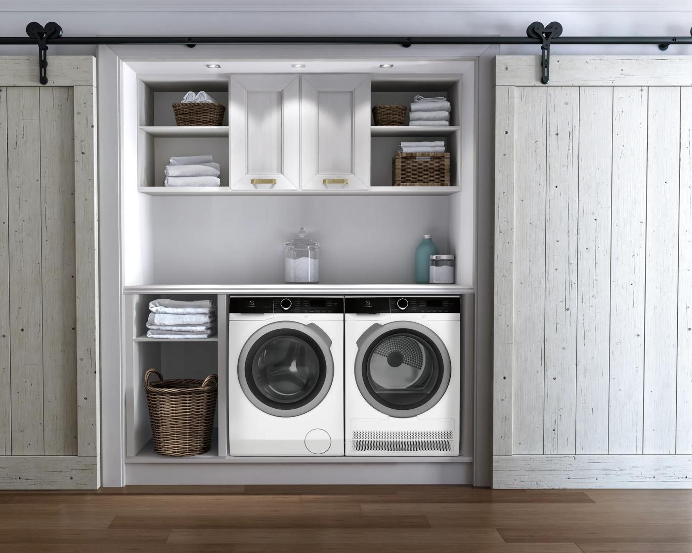 Built-in laundry nook with white front load washer and compact front load dryer surrounded by storage shelves and cabinets