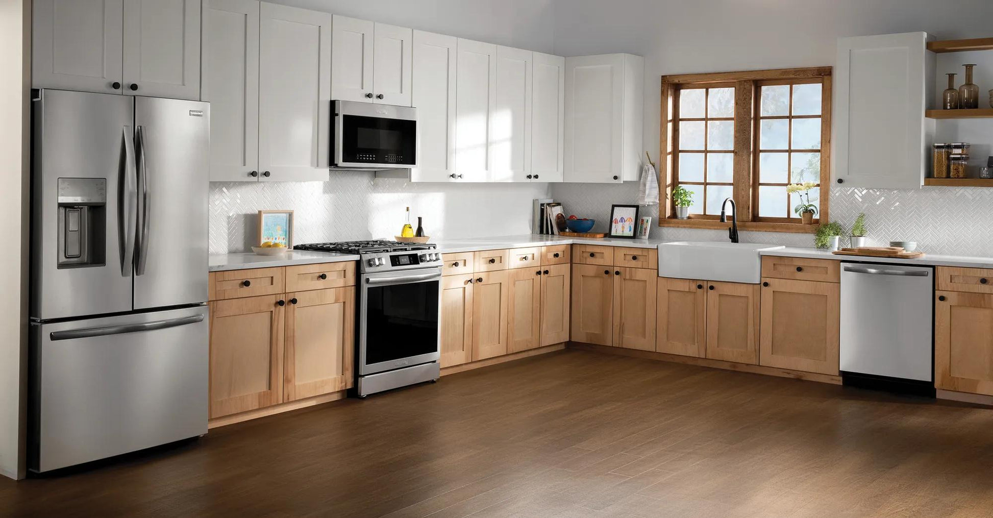 Spacious kitchen with light wood lower cabinets, white upper cabinets, stainless steel dishwasher and appliances from kitchenware collection