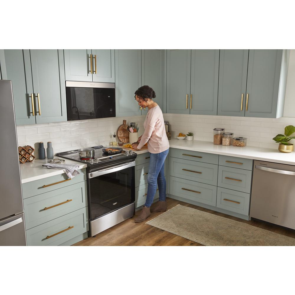 Contemporary kitchen with flush mount black microwave and stainless steel stove, soft green cabinets, and gold hardware accents