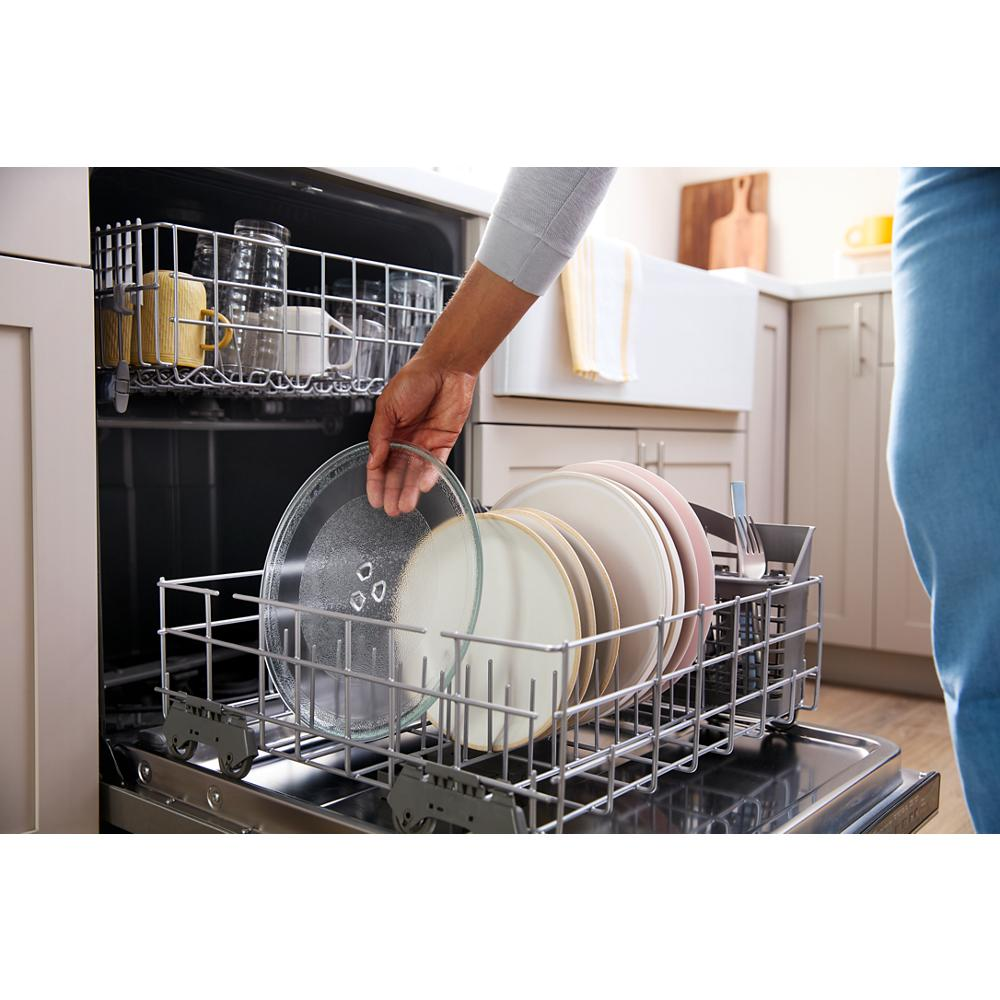 Hand placing a glass plate inside the lower rack of a modern dishwasher in a bright kitchen setting