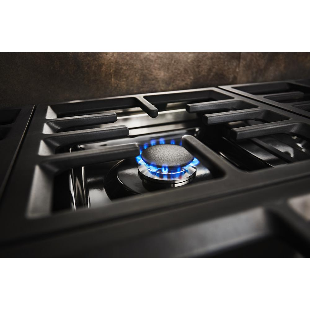 Close-up of a gas burner with blue flame and cast iron grates on a commercial-style kitchen cooktop