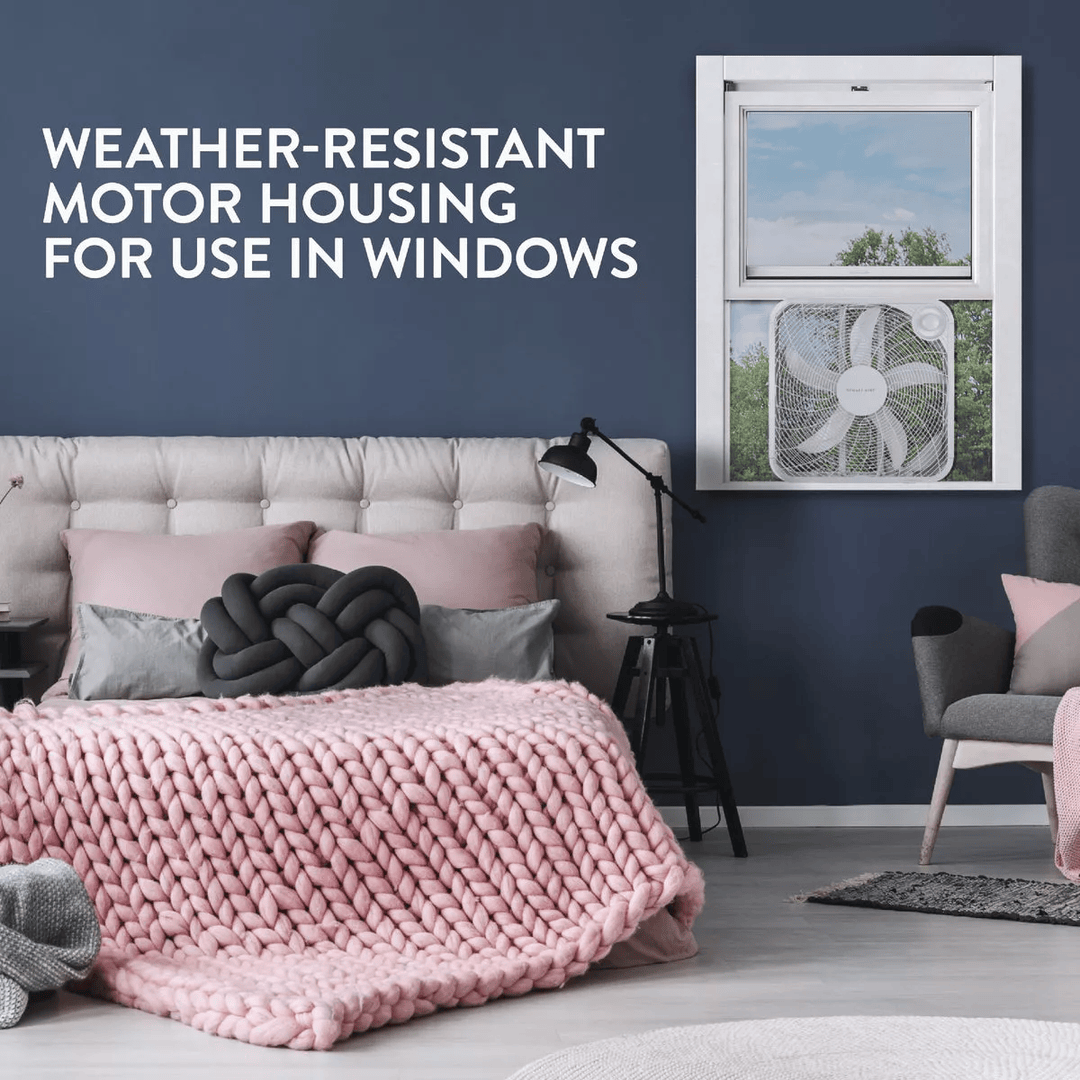 White weather-resistant box fan mounted in a window above a gray bed in a modern bedroom setting under $50 collection