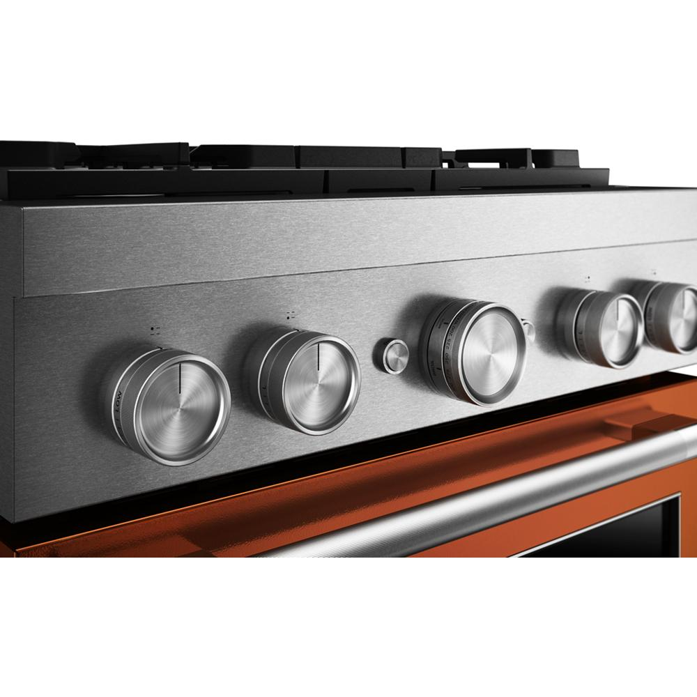 Close-up of stainless steel control panel with five brushed metal knobs on a KitchenAid commercial-style range